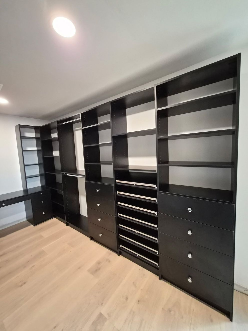 Large Black walk-in closet with wood floors