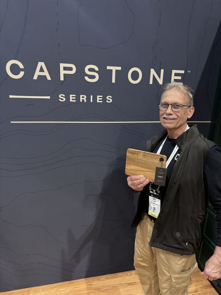 Older man in front of capstone sign