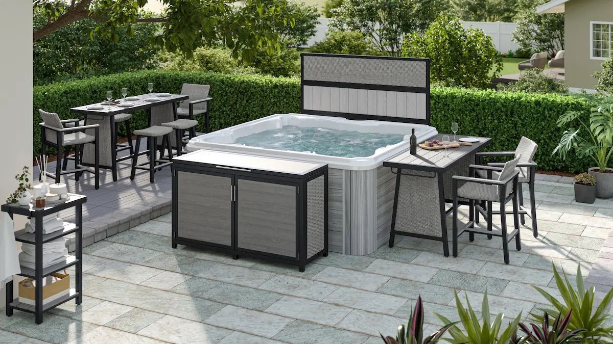 Outdoor patio with a gray hot tub, lounge chairs, and dining tables on a stone terrace