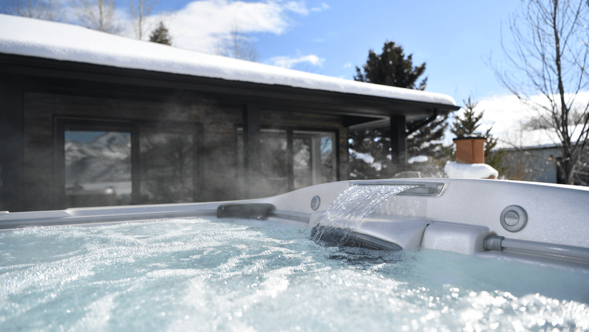 Hot tub bubbling outside a modern house in a snowy winter landscape