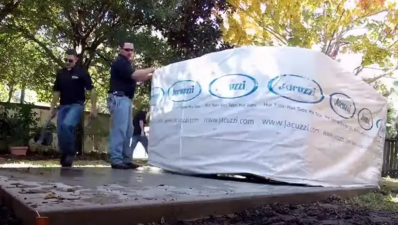 Two men beside a white branded tent on a platform outdoors, one adjusting the tent wall.