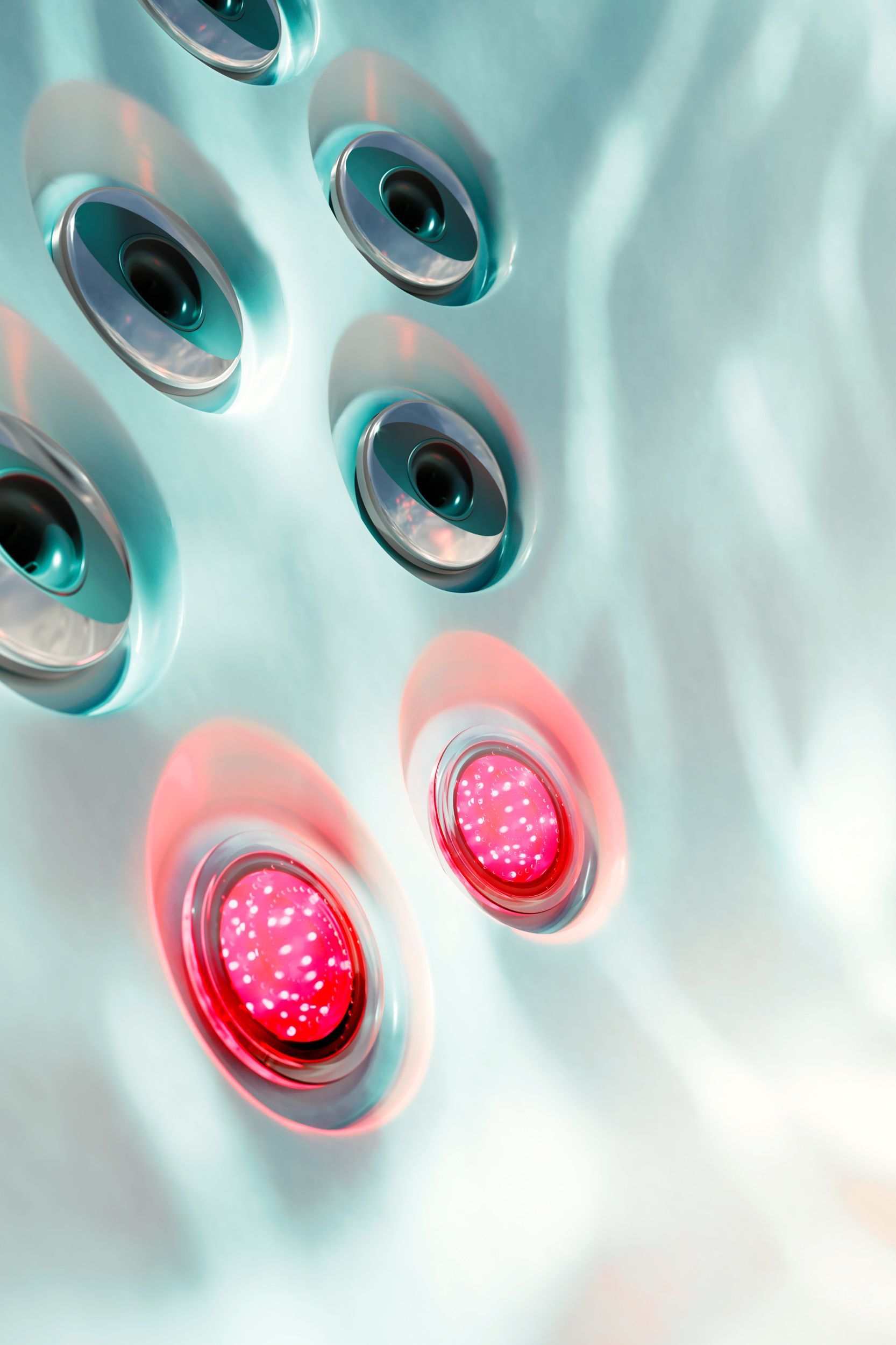 Close-up of metallic buttons with two glowing red lights on a pale aqua surface