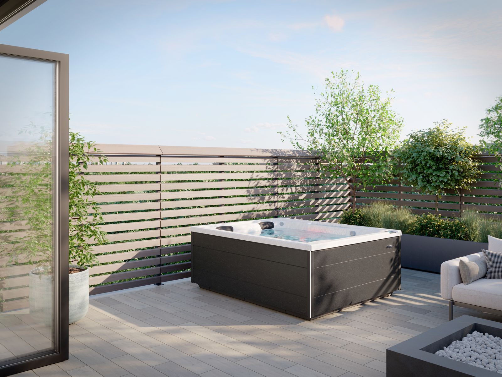 Modern patio with a hot tub, gray seating, and wooden privacy fence under a bright sky