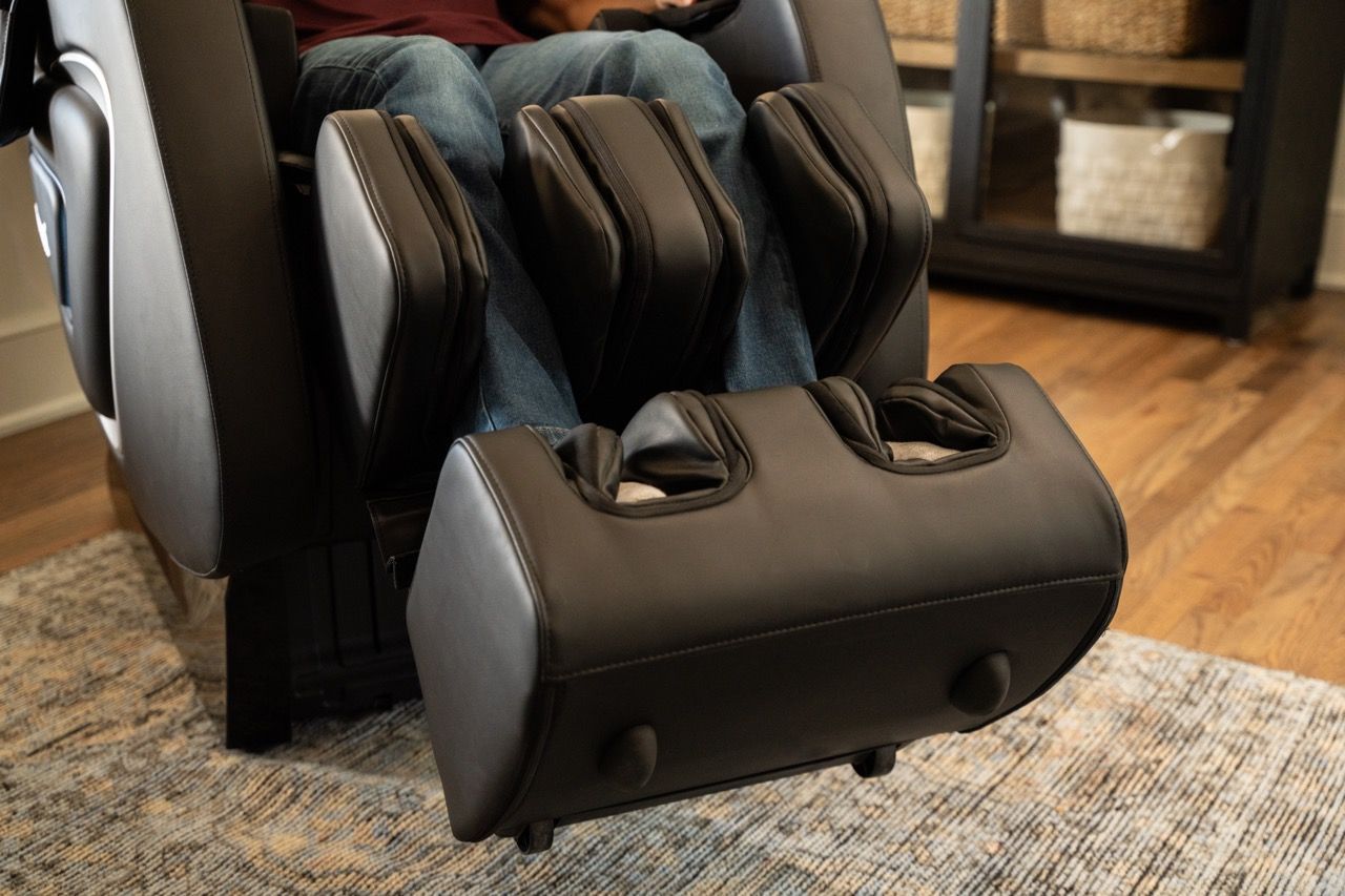 Black massage chair with foot and calf massager on a rug in a living room