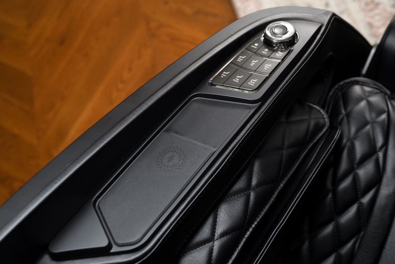 Luxury car center console with black quilted seat and metallic control panel next to it