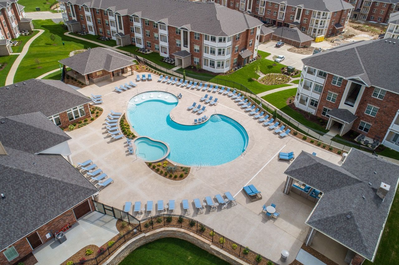 Aerial view of a resort pool courtyard with lounge chairs and apartment buildings surrounding it