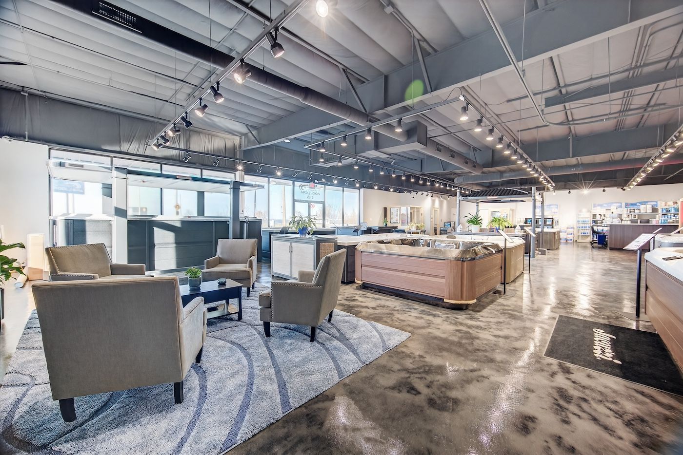 Modern office lounge with sofas, chairs, tables, and exposed ceilings in a bright open workspace