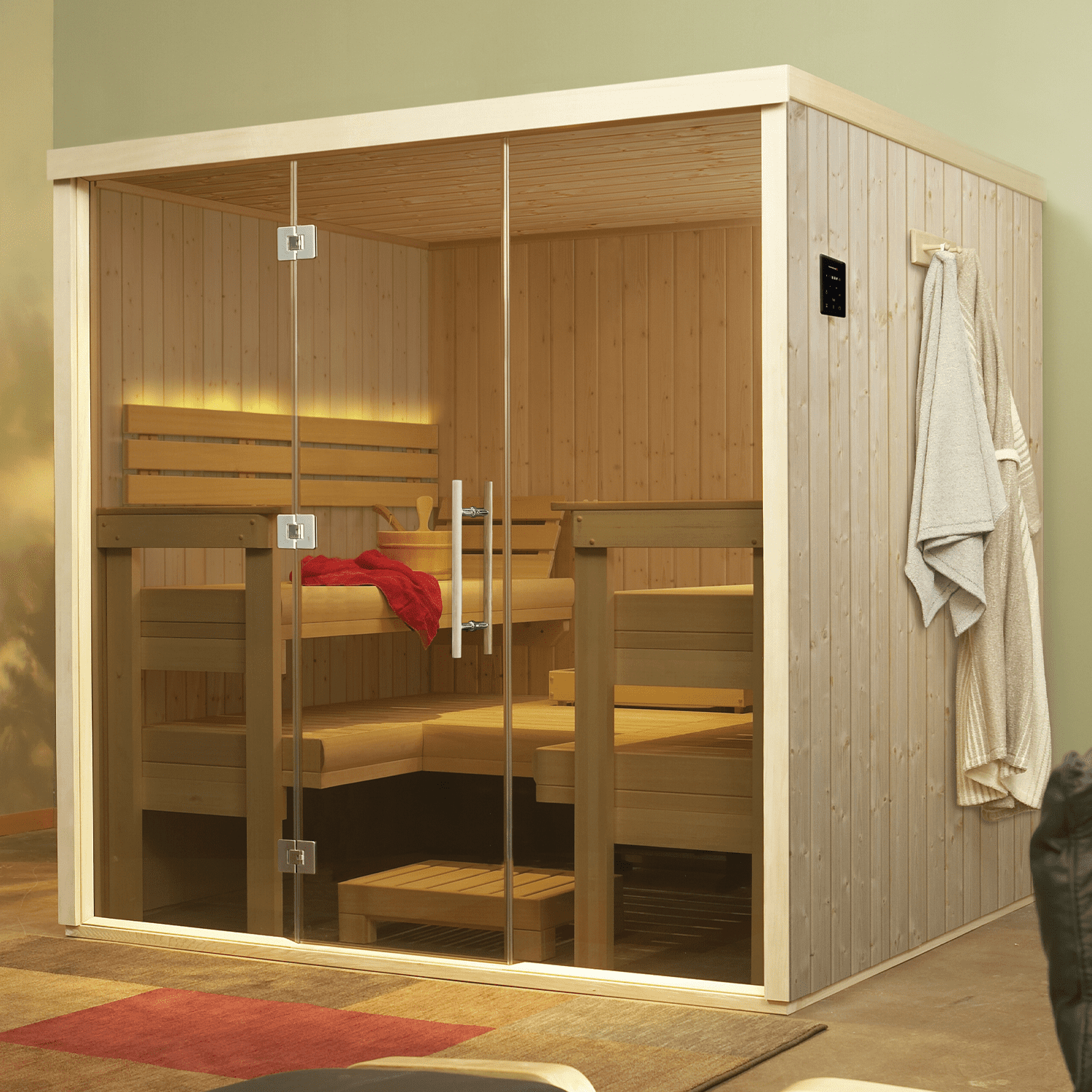 Glass sauna with wooden benches and shelves, towels hanging outside, in a modern room
