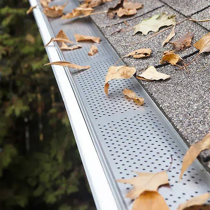 A close up of a gutter with leaves on it.