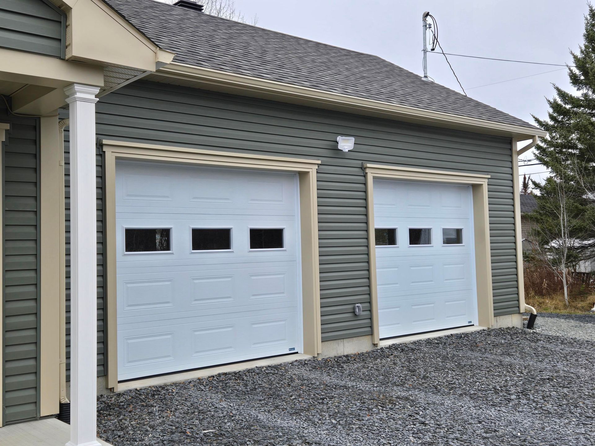 There are two garage doors on the side of a house.