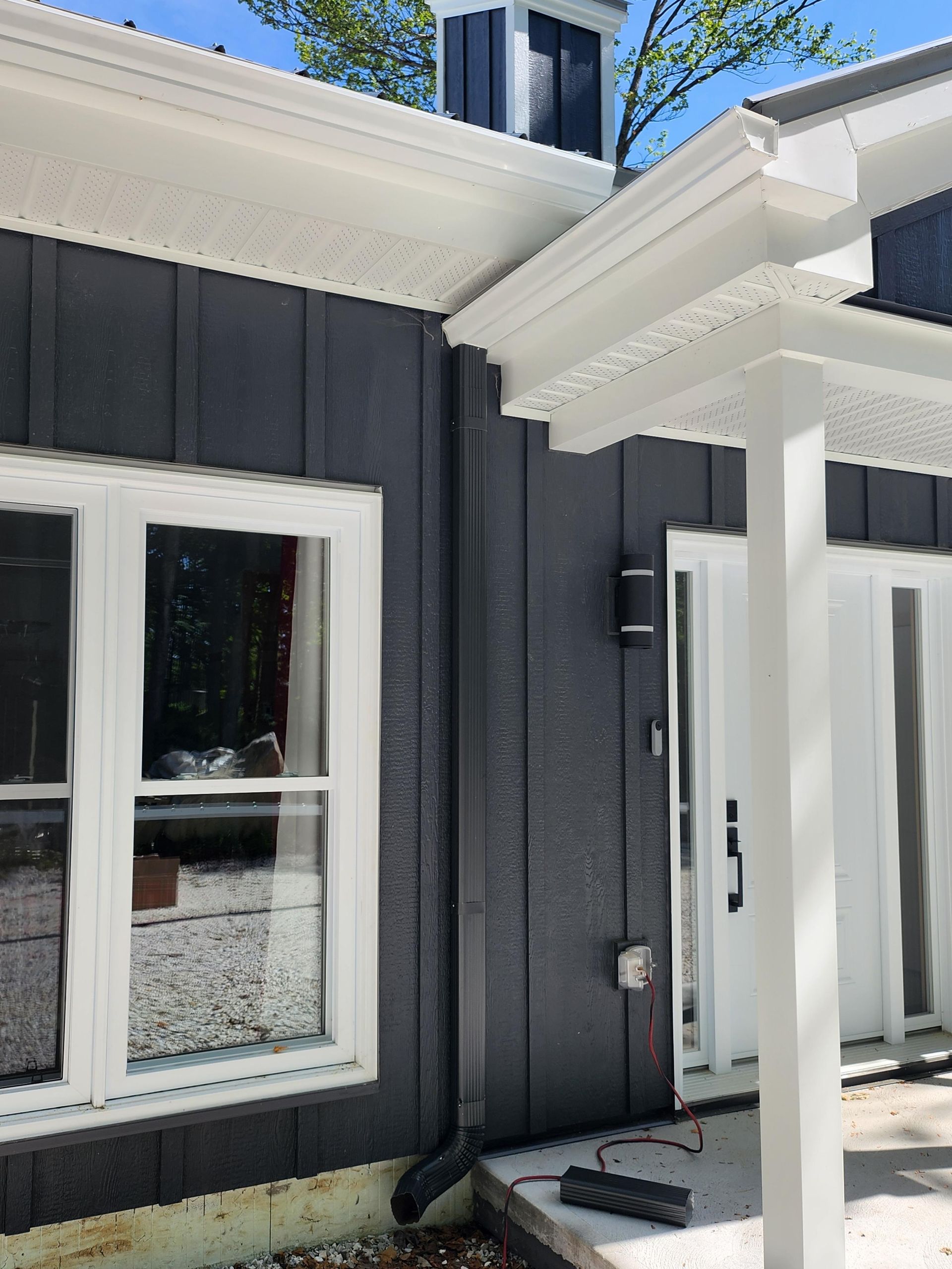 A black and white house with a porch and a roof.