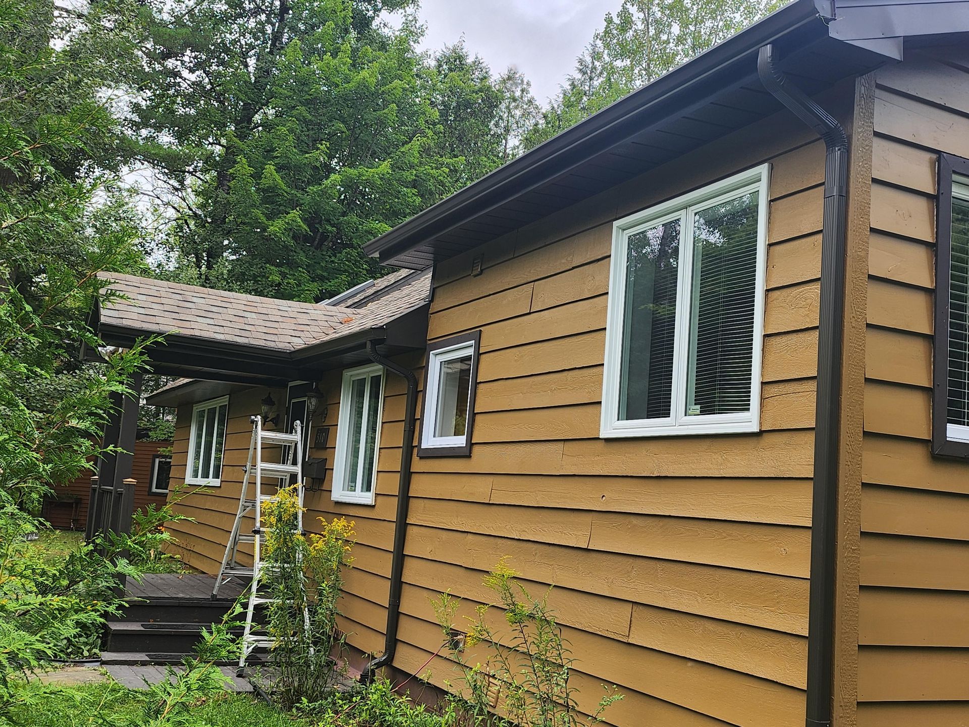 A yellow house with a ladder on the side of it.