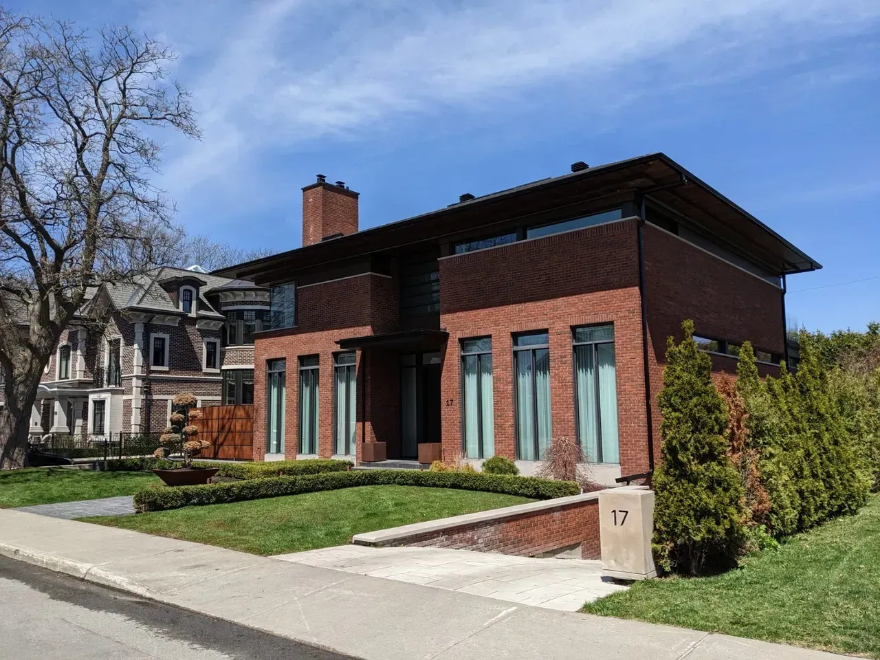 A large brick house with a lot of windows is sitting on a lush green lawn.