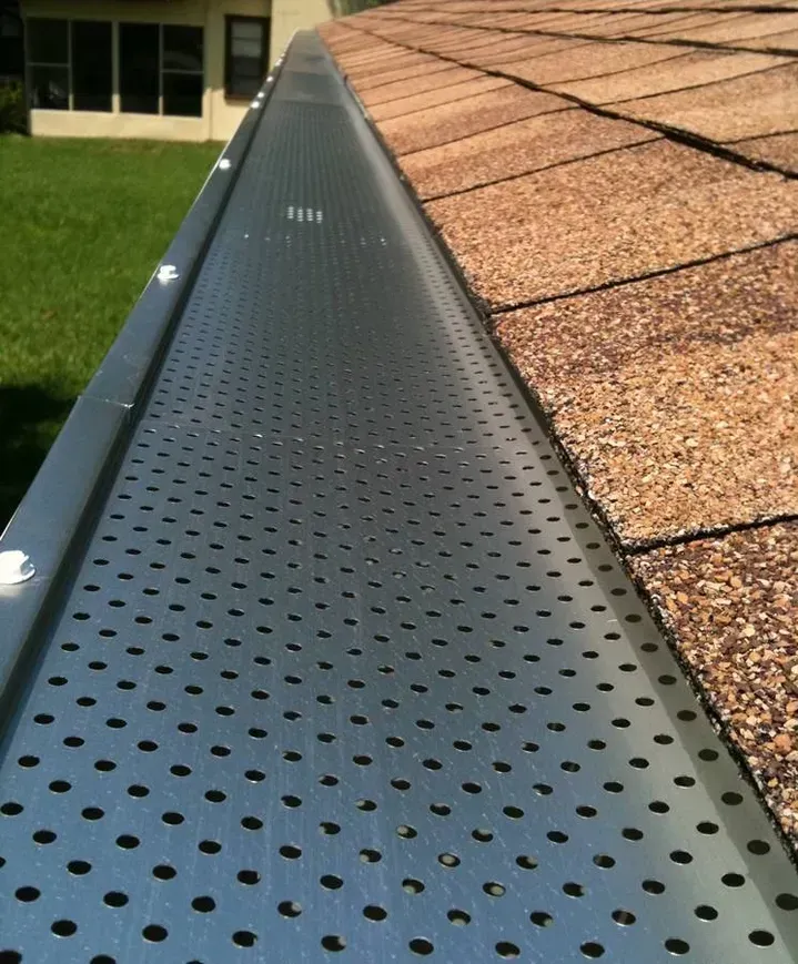 A gutter with holes in it is attached to a roof