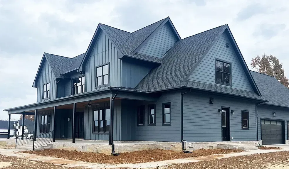 A large blue house with a black roof and a porch.
