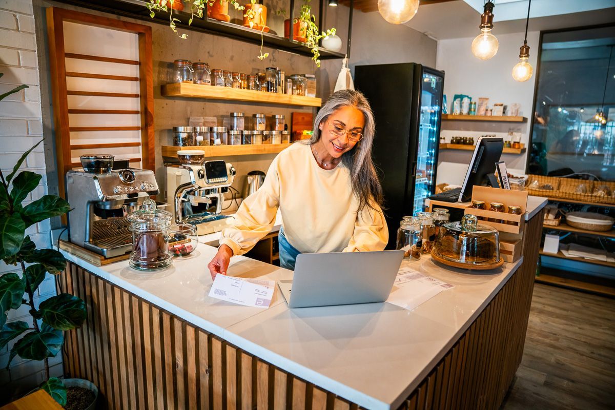 Business owner reviews documents and notes at a counter while working on business receipts.