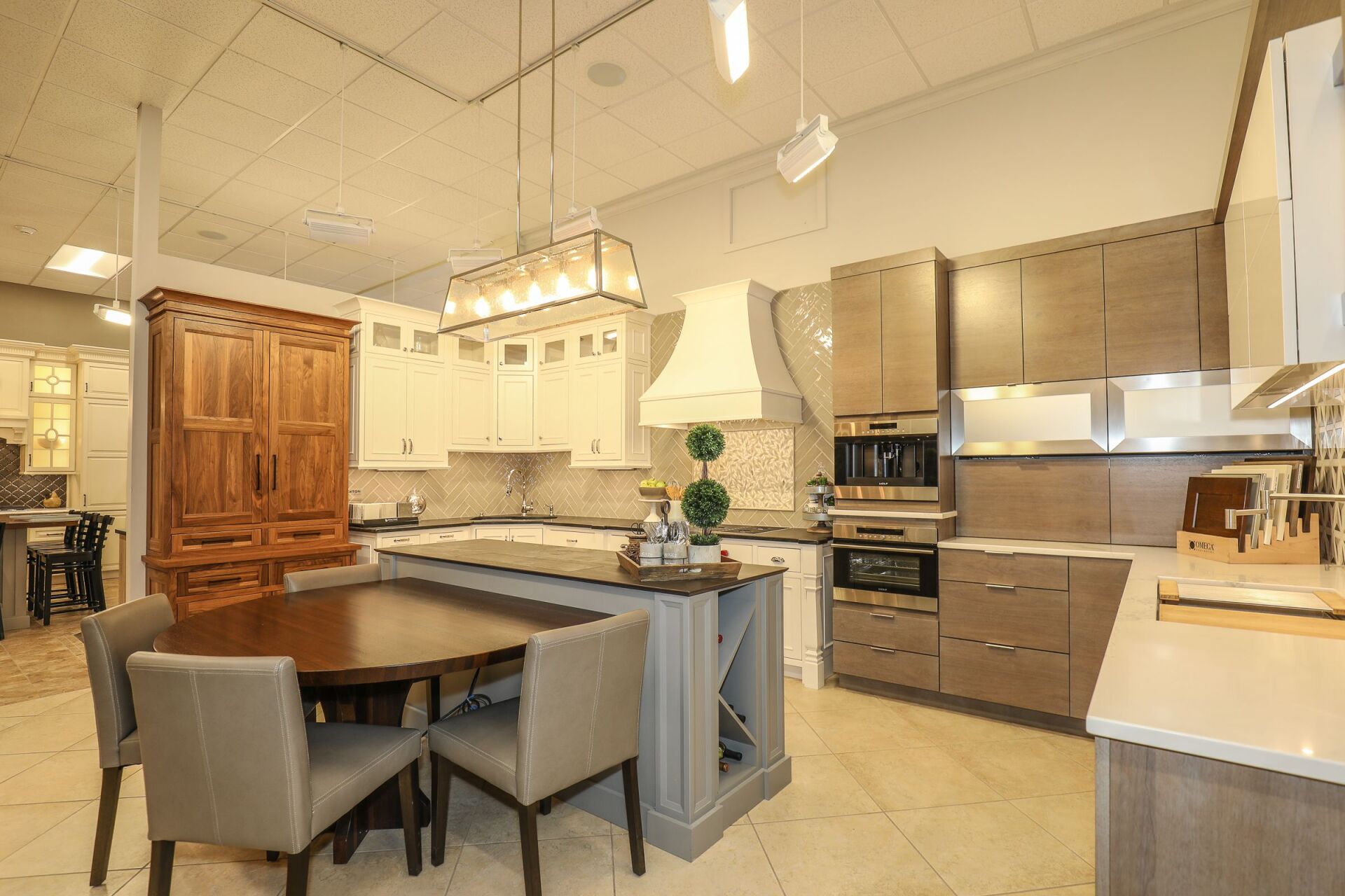 Modern kitchen with wood cabinets, stainless steel appliances, island, and dining table under pendant lights