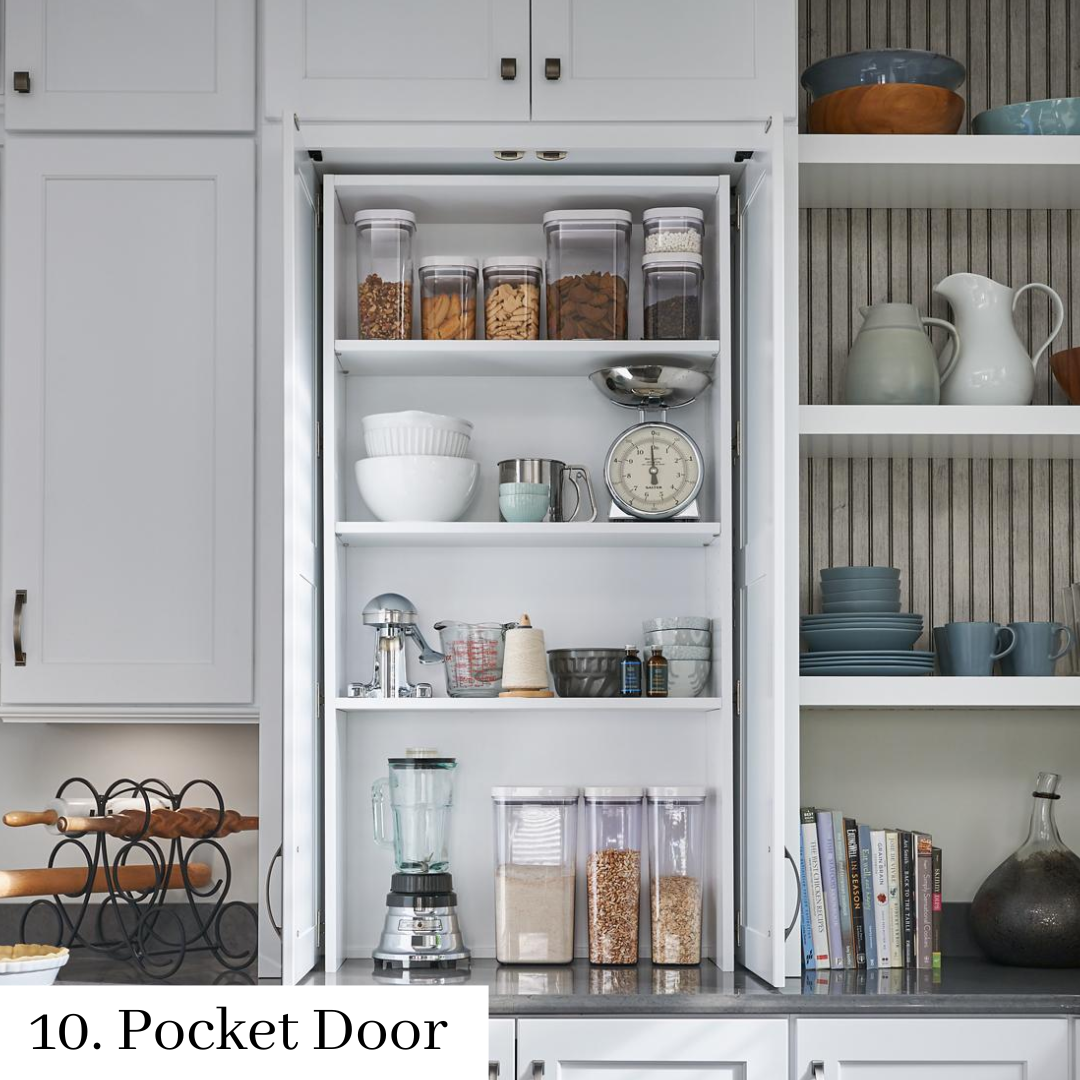 Open pantry with shelves of dishes, jars, and kitchenware in a light gray kitchen.