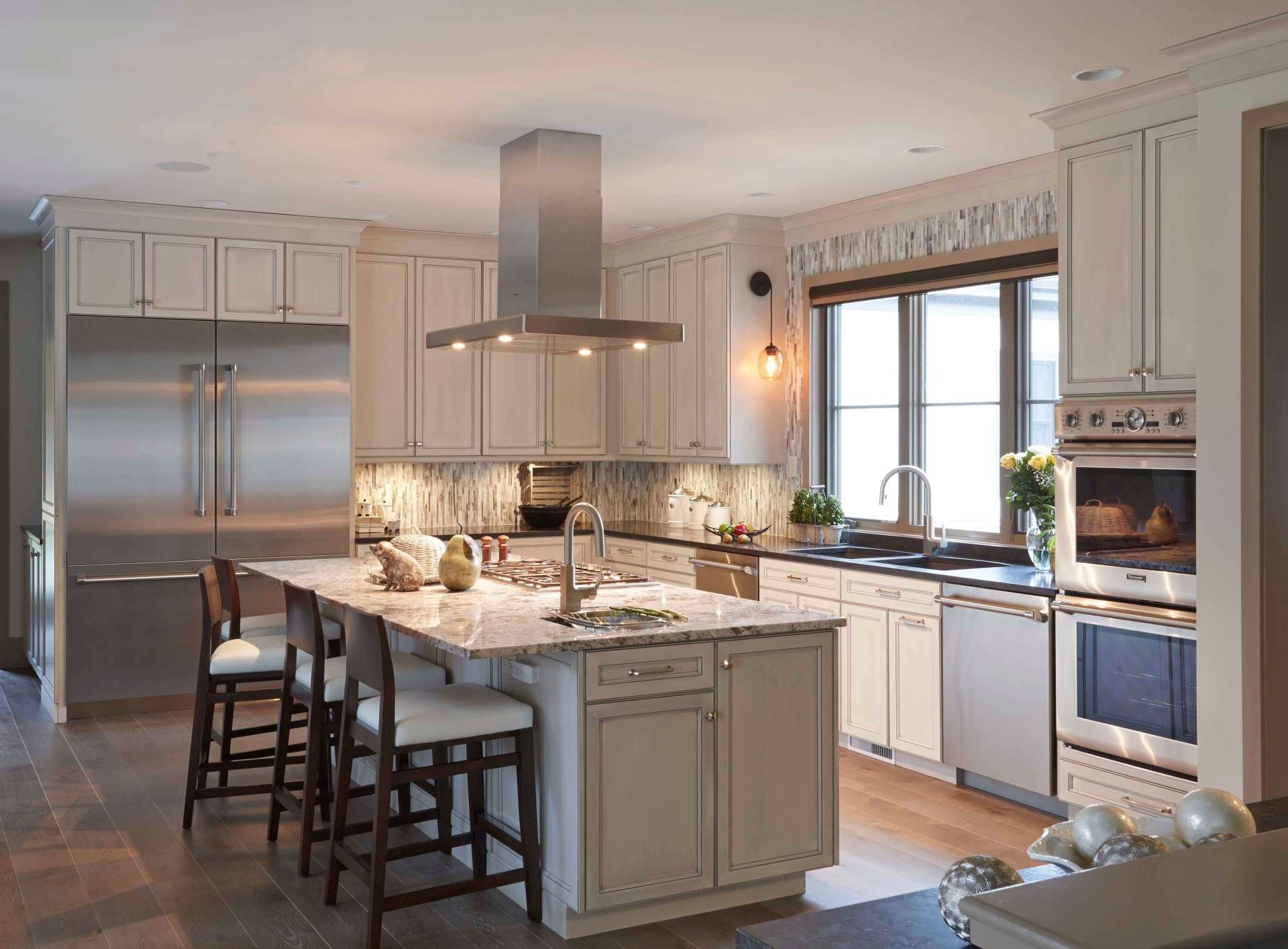 Modern kitchen with stainless steel appliances, large island, white cabinetry, and bright windows