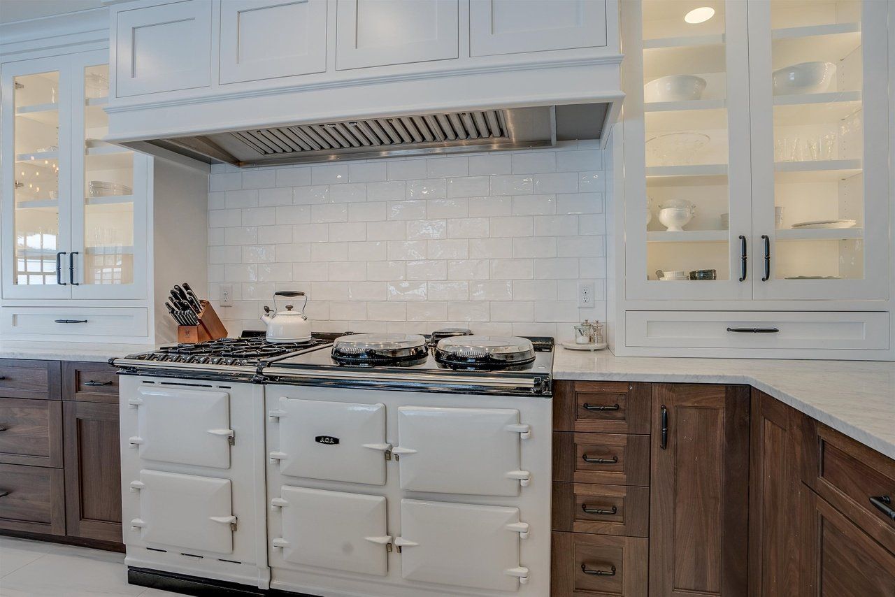 White kitchen with vintage stove, herringbone tile backsplash, and dark wood lower cabinets