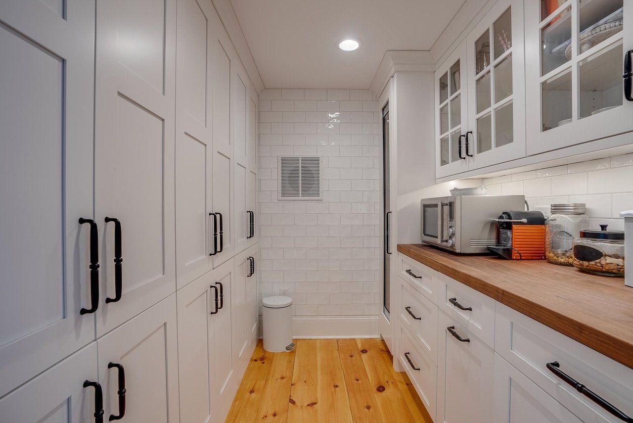 Bright white galley kitchen with wood countertops, cabinets, and a hardwood floor