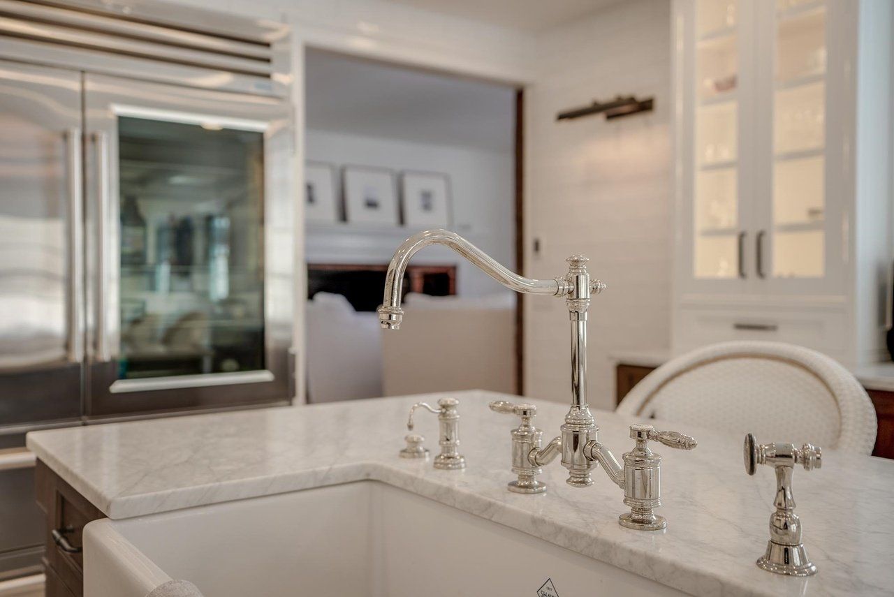 Bright modern kitchen with white marble sink, chrome faucet, and glass-front cabinets