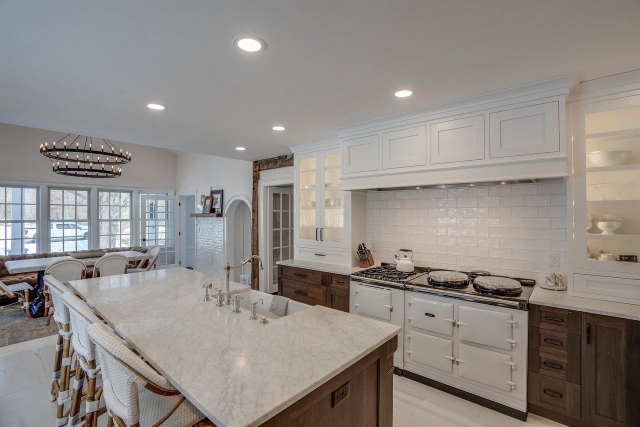 Bright modern kitchen with large island, white cabinets, marble countertops, and adjoining dining area