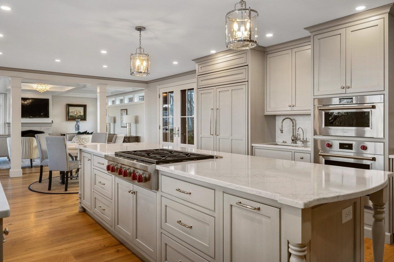 Bright modern kitchen with white cabinetry, marble island, and stainless steel appliances