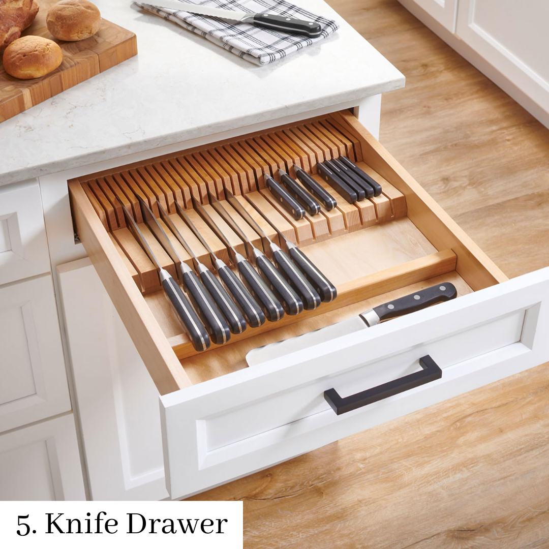 Open kitchen drawer with organized wooden and black knife set in a countertop knife block