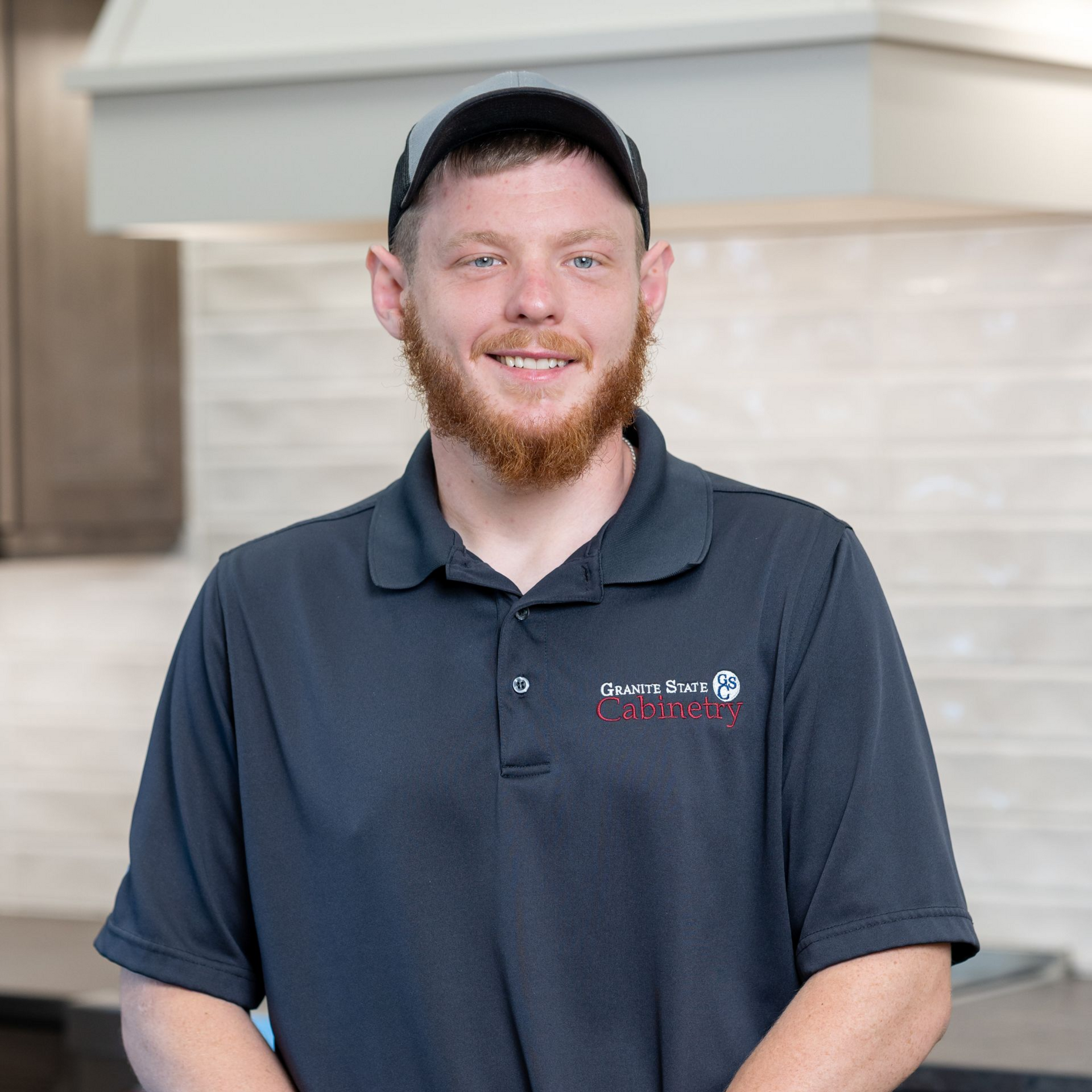 Smiling person in a black cap and maroon shirt in a bright kitchen