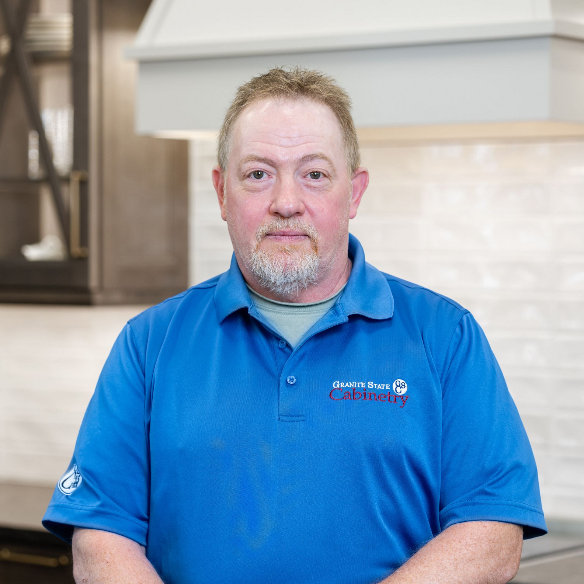 Portrait of a bald man wearing glasses and a blue shirt in a kitchen