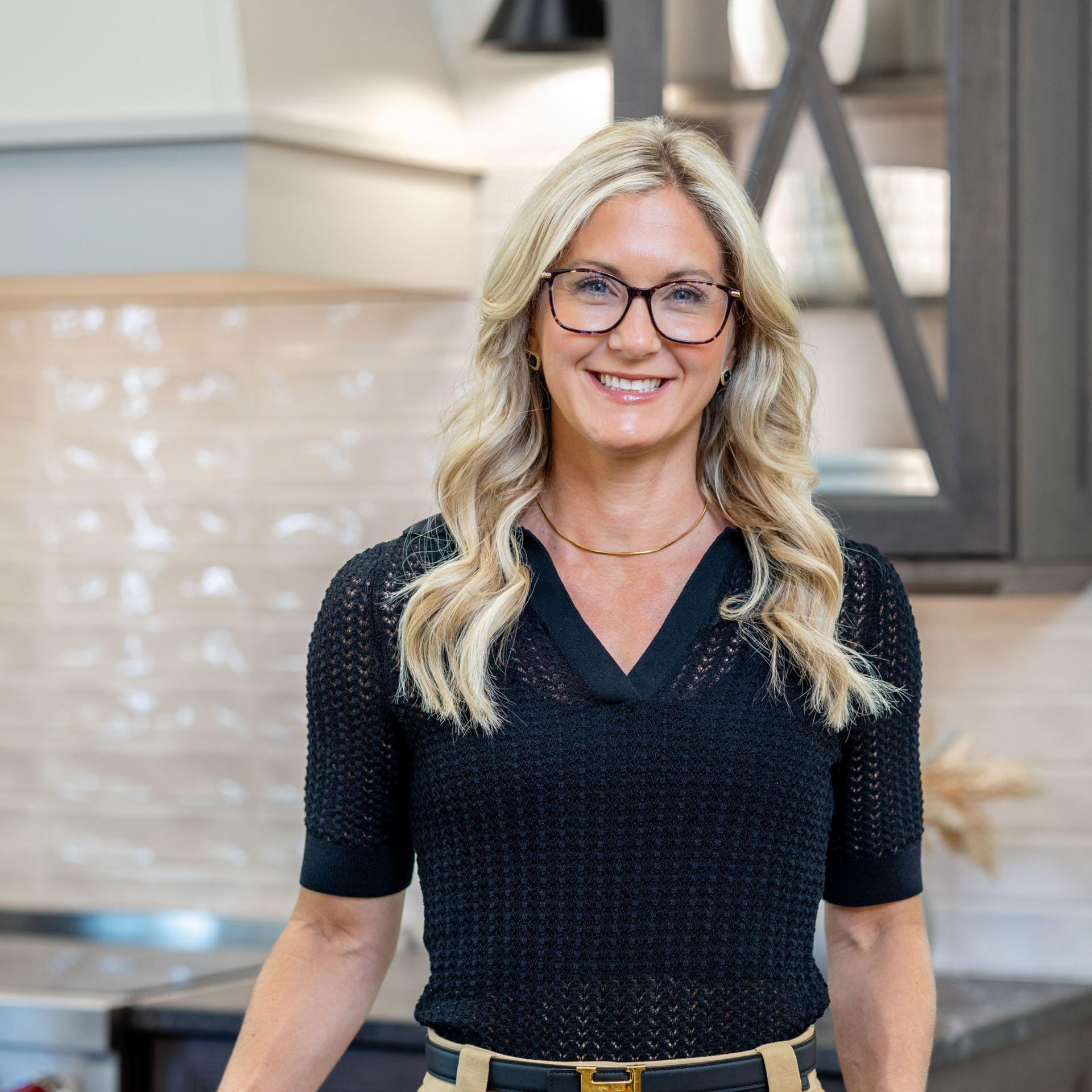 Smiling woman in a striped shirt standing in a bright kitchen with marble countertops