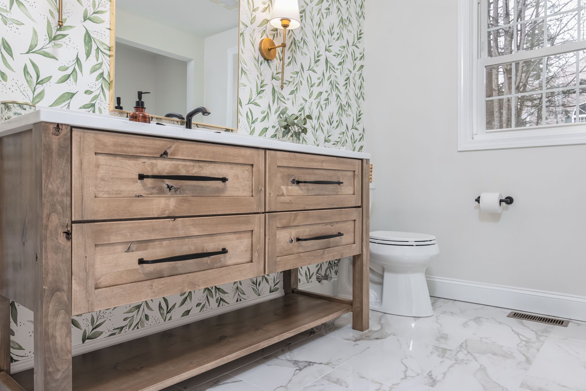 Wood vanity with double sinks in a bright bathroom, with white tile floor, toilet, and floral wallpaper