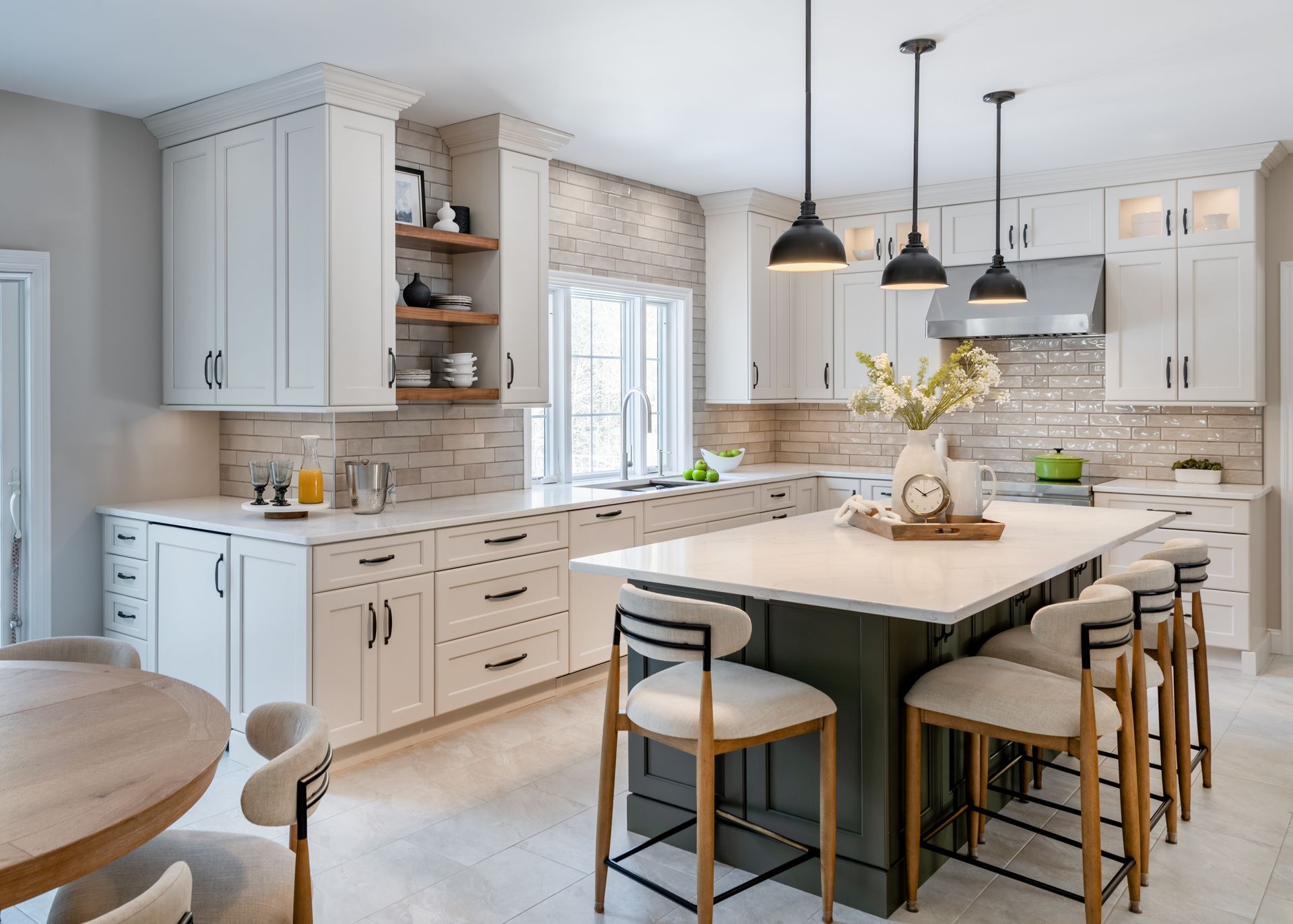 Bright white kitchen with a large island, pendant lights, bar stools, and marble backsplash.
