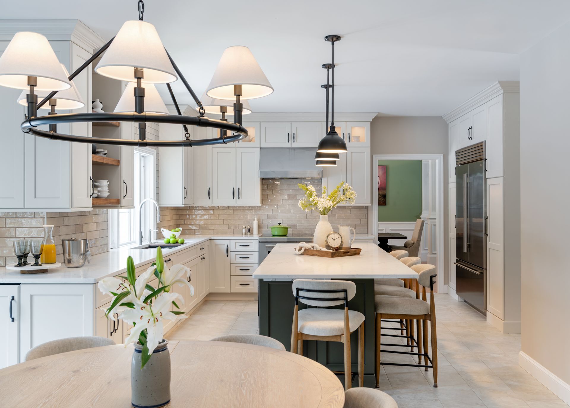 Bright modern kitchen with white cabinets, island seating, and a black chandelier