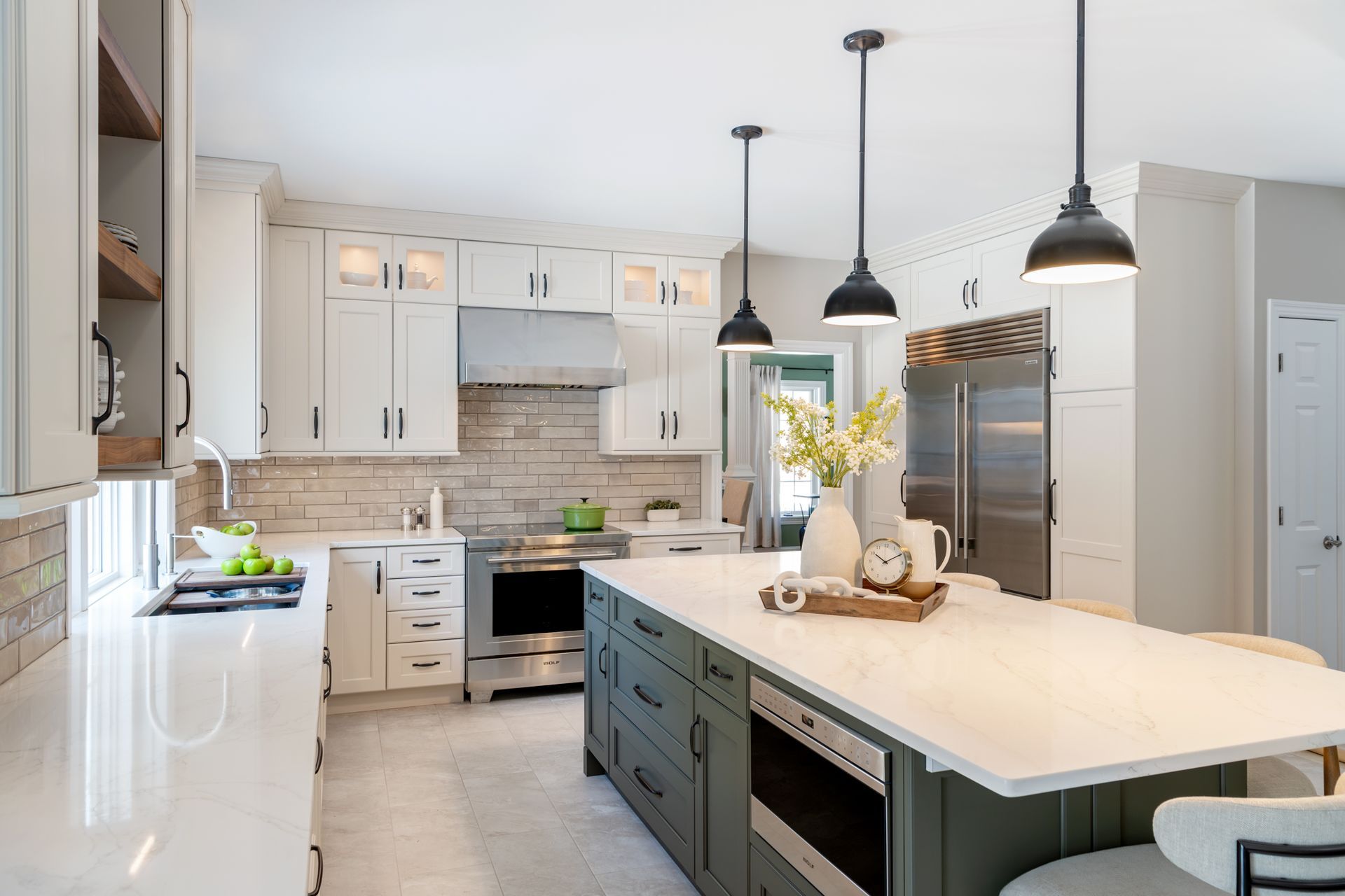 Bright modern kitchen with white cabinets, marble island, black pendant lights, and stainless steel appliances