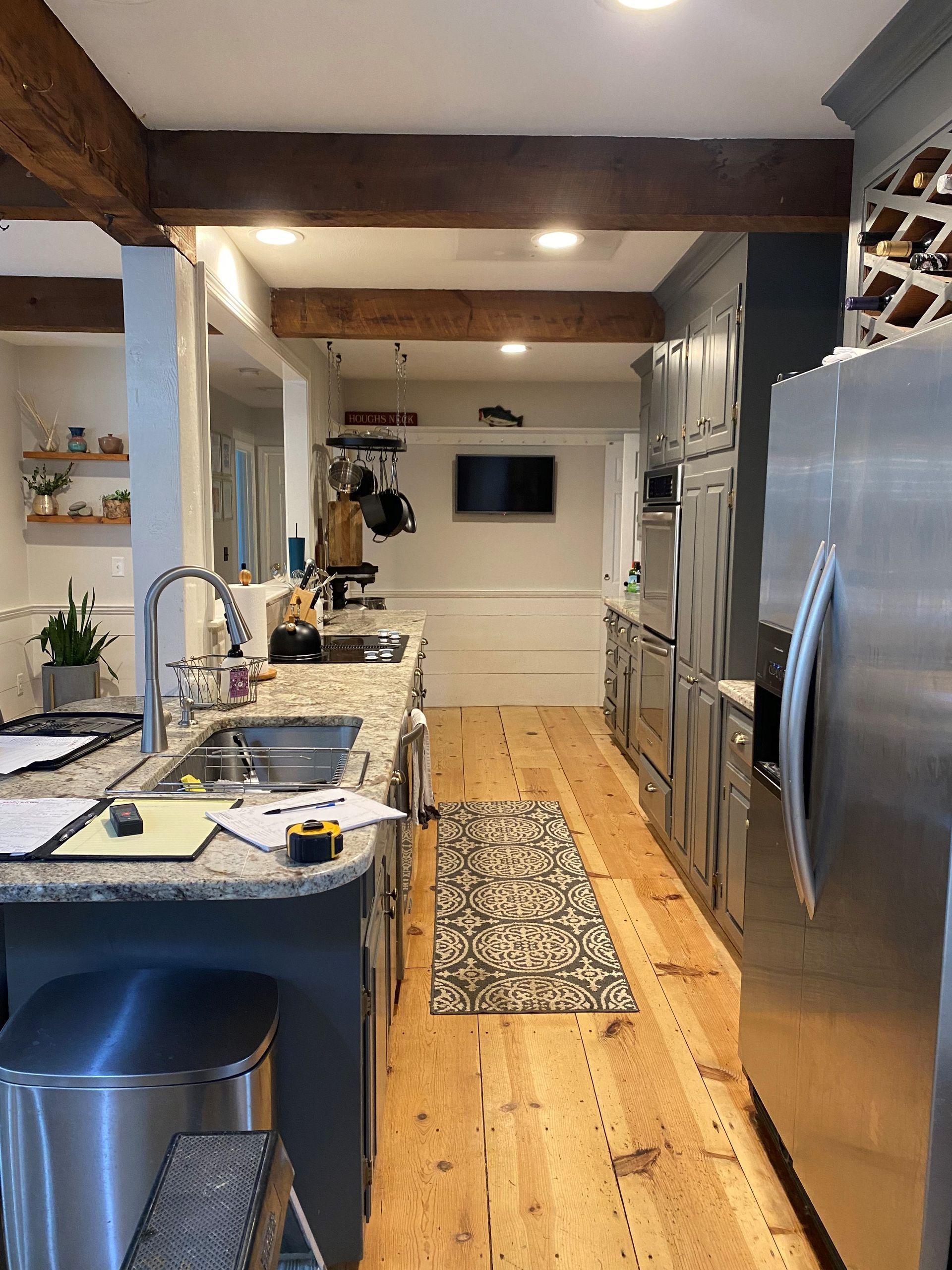 Bright modern kitchen with stainless steel fridge, island sink, wood floors, and recessed lighting
