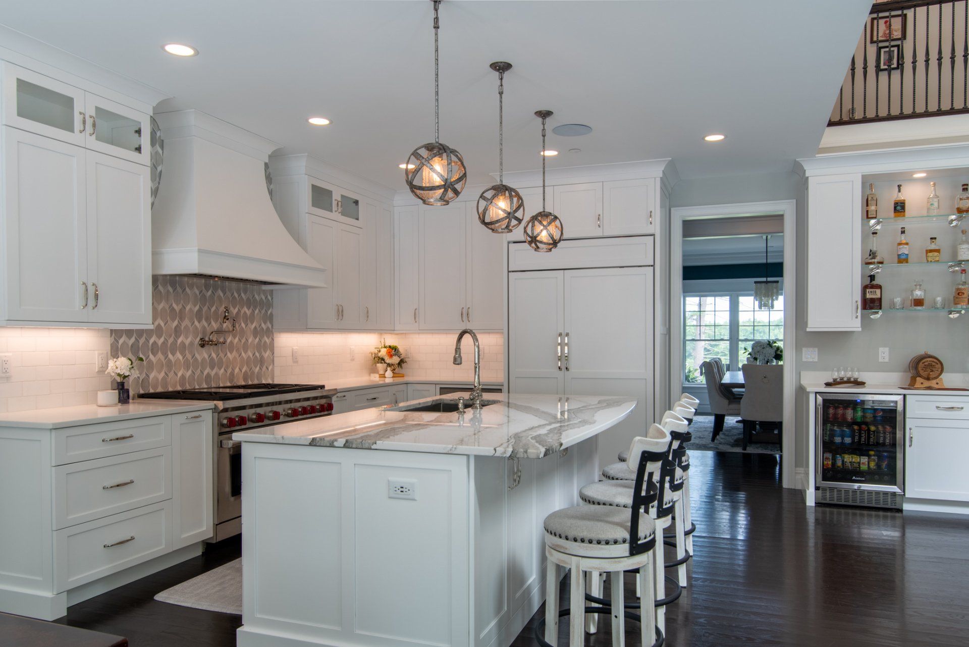 Bright white kitchen with marble island, pendant lights, and dark hardwood floors