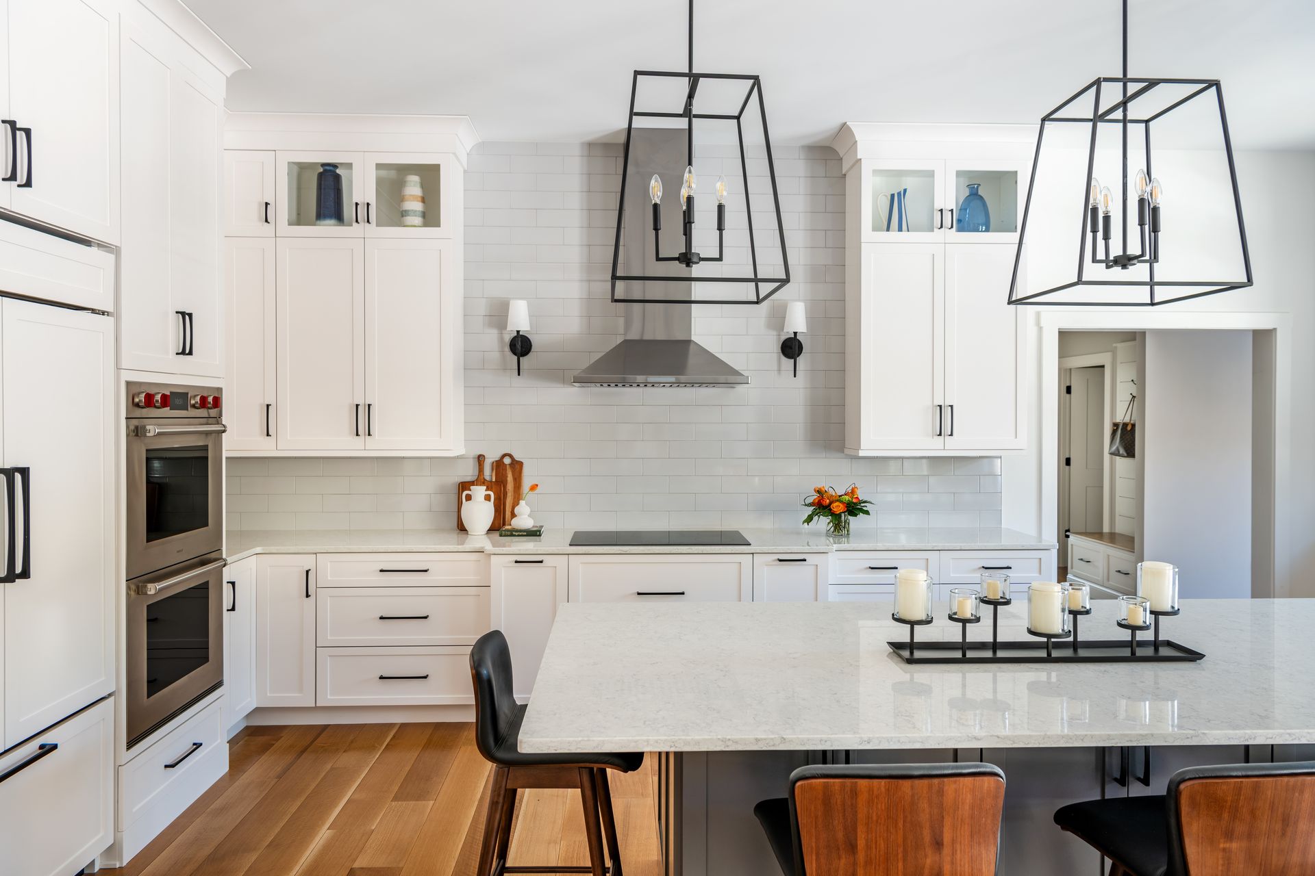 Modern white kitchen with island, black pendant lights, and built-in appliances