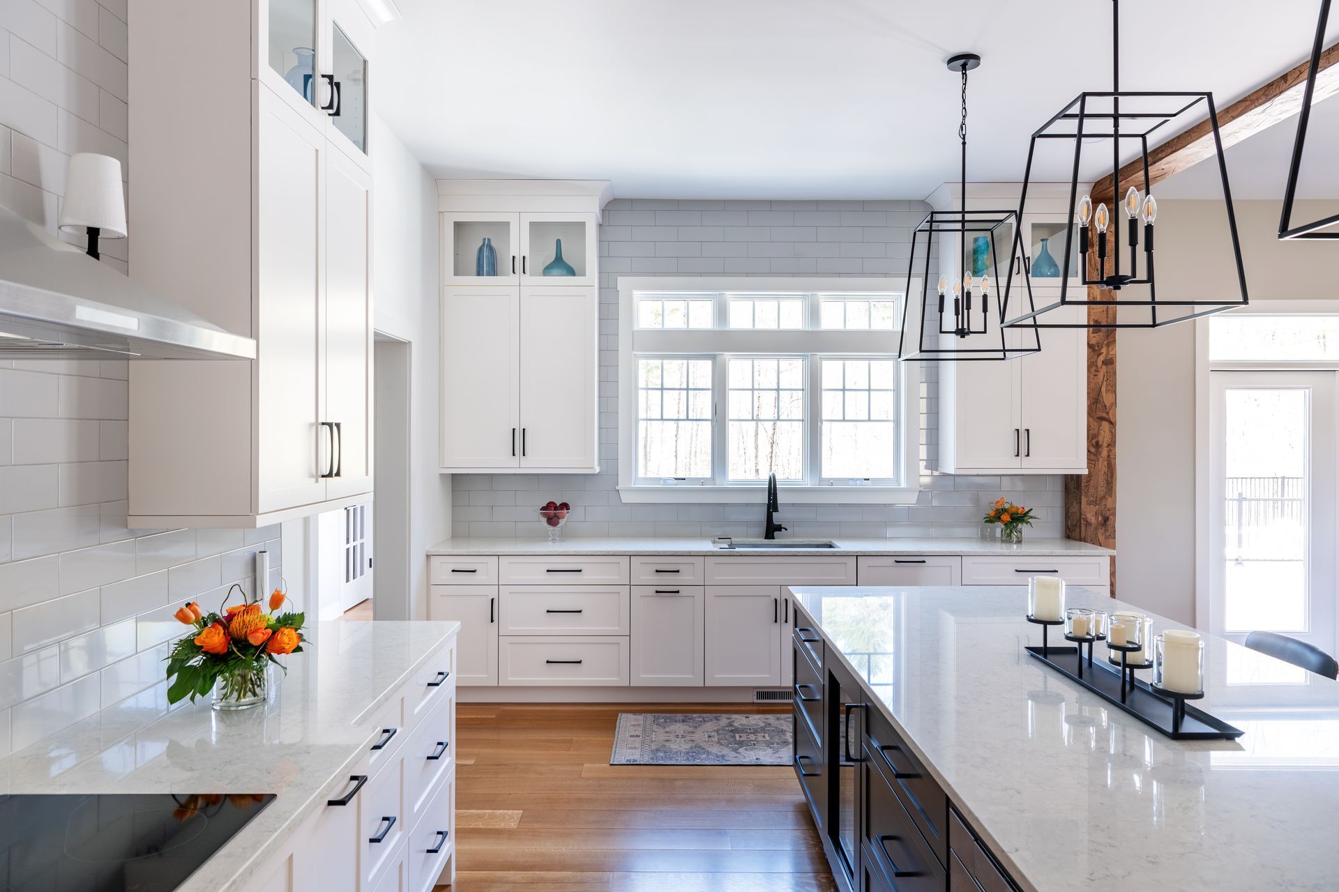 Bright white modern kitchen with island, pendant lights, and large window over a sink