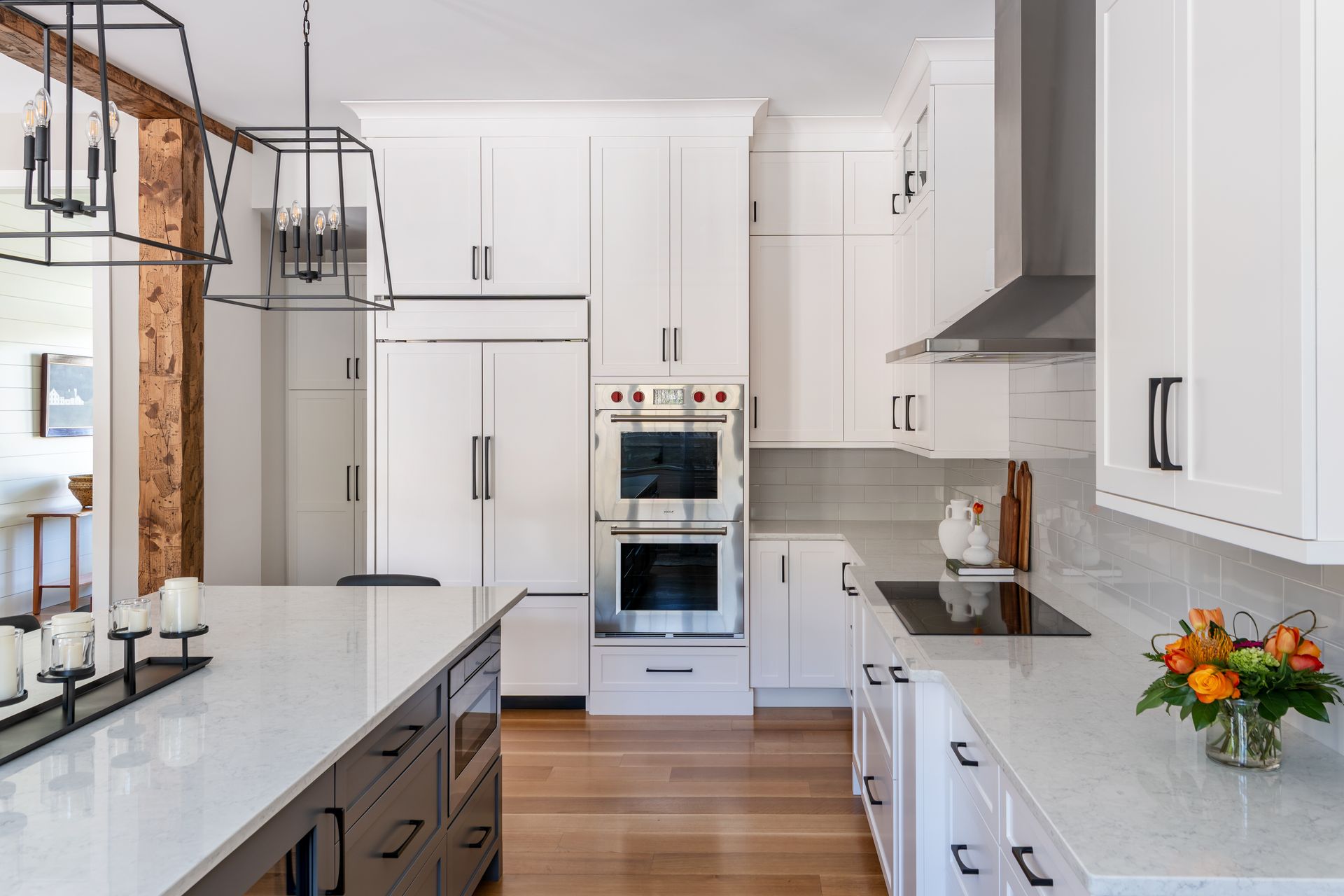 Bright modern kitchen with white cabinets, marble counters, island, and stainless steel appliances