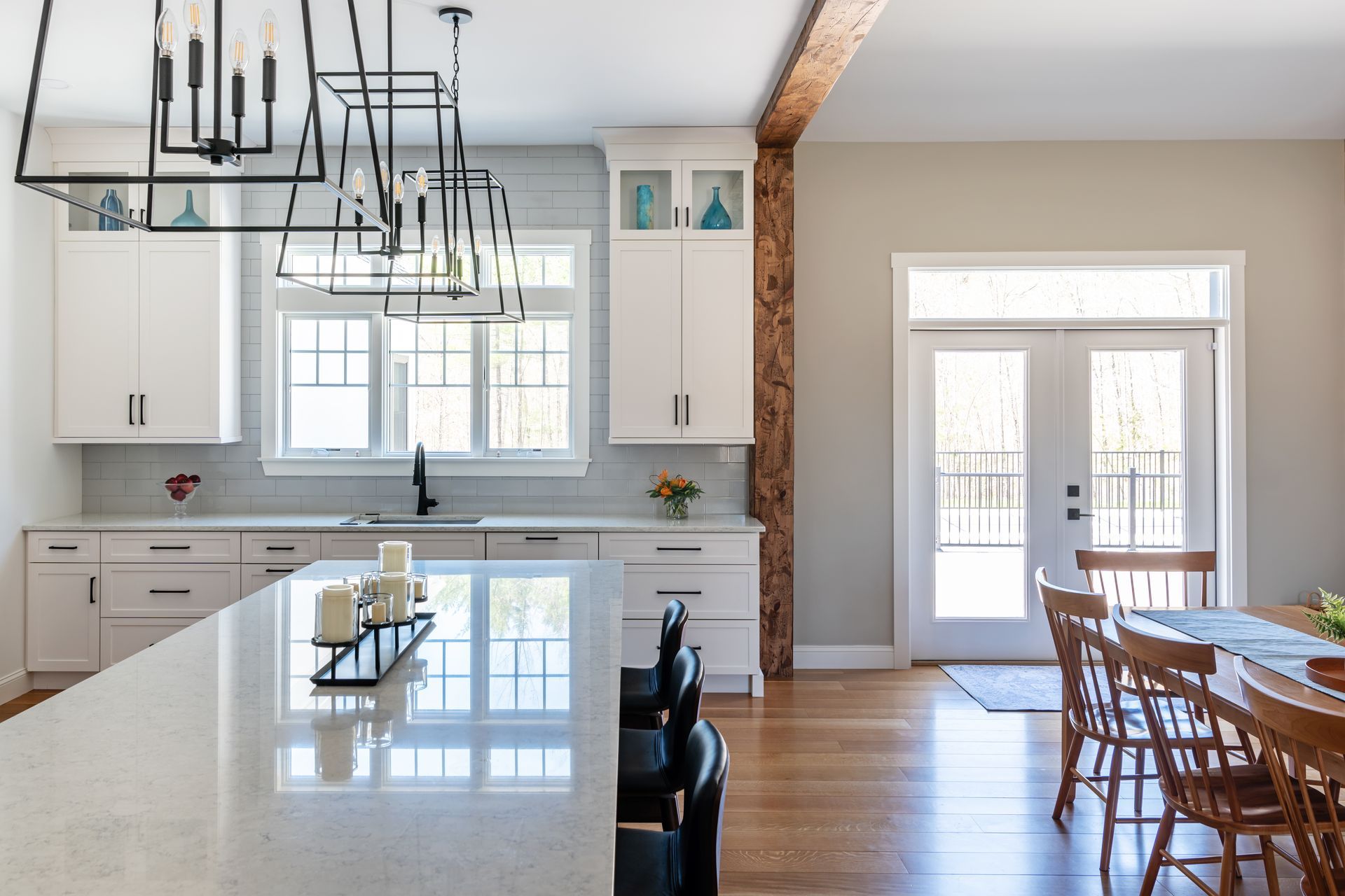 Bright, modern kitchen with white cabinets, island, pendant lights, and adjoining dining area.