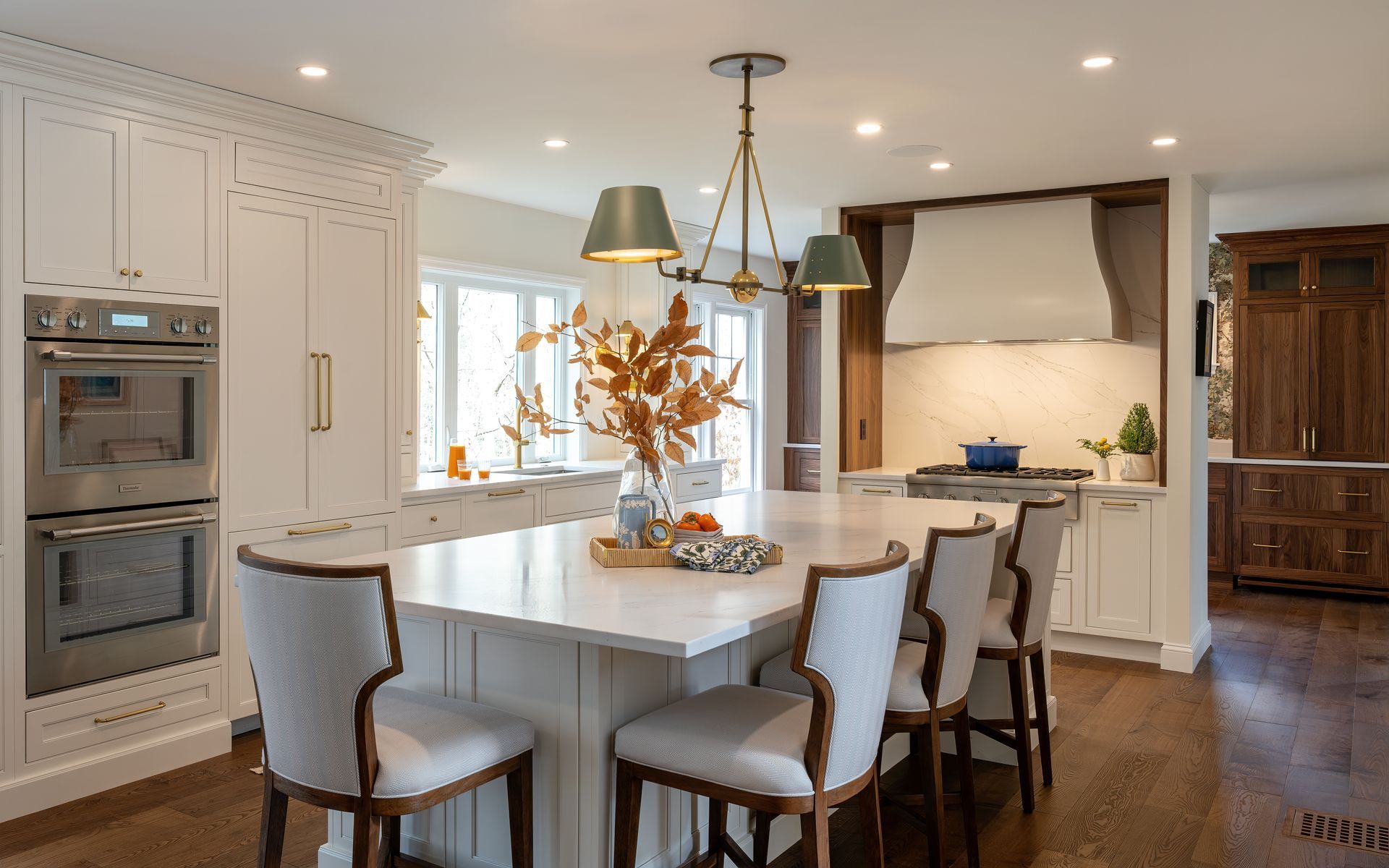 Bright modern kitchen with a large island, white cabinets, pendant light, and wood floor