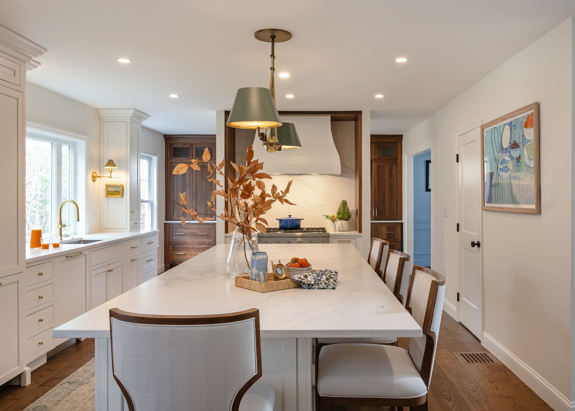 Bright kitchen with a large island, pendant lights, white cabinets, and a dining table with chairs.