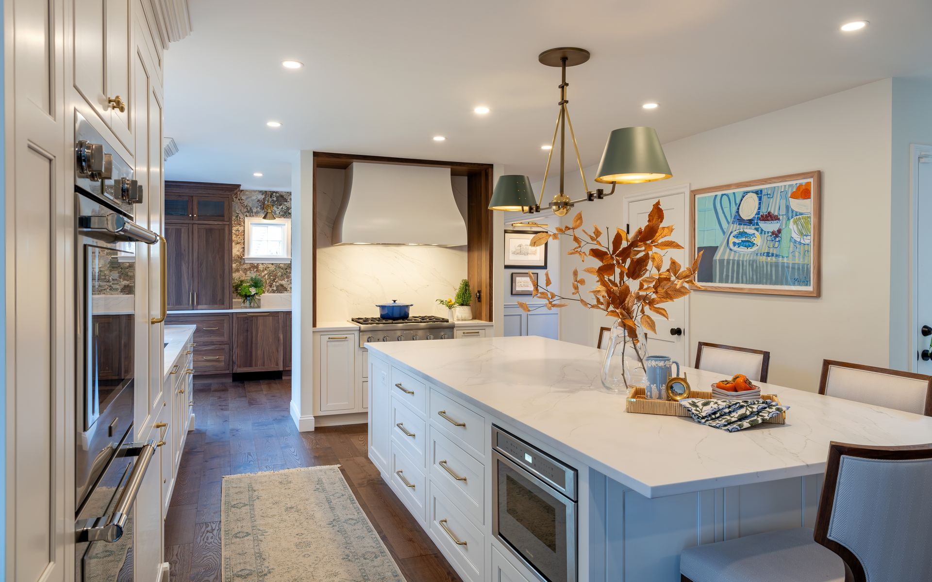 Bright modern kitchen with white island, pendant lights, stainless appliances, and bowl of fruit