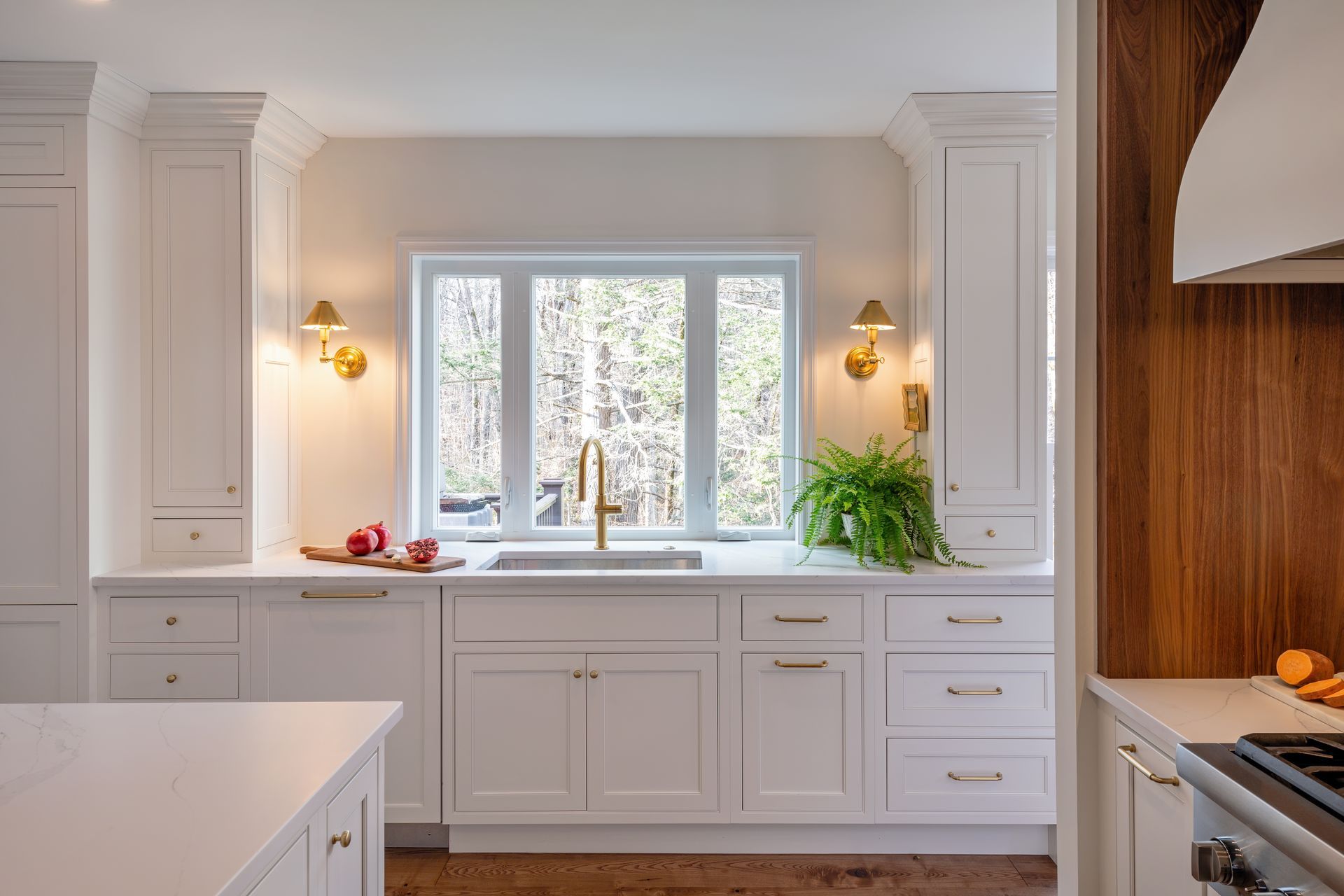 Bright white kitchen with a window over the sink, wood accents, and daylight outside