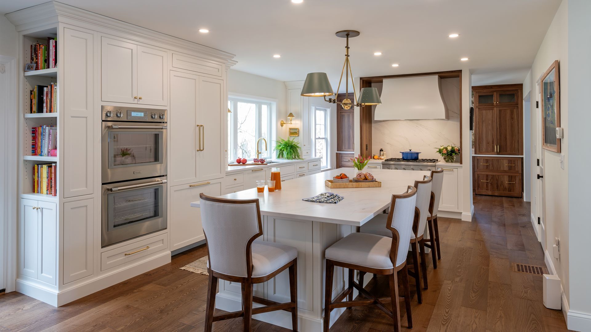 Bright modern kitchen with a large island, white cabinetry, pendant lights, and hardwood floors