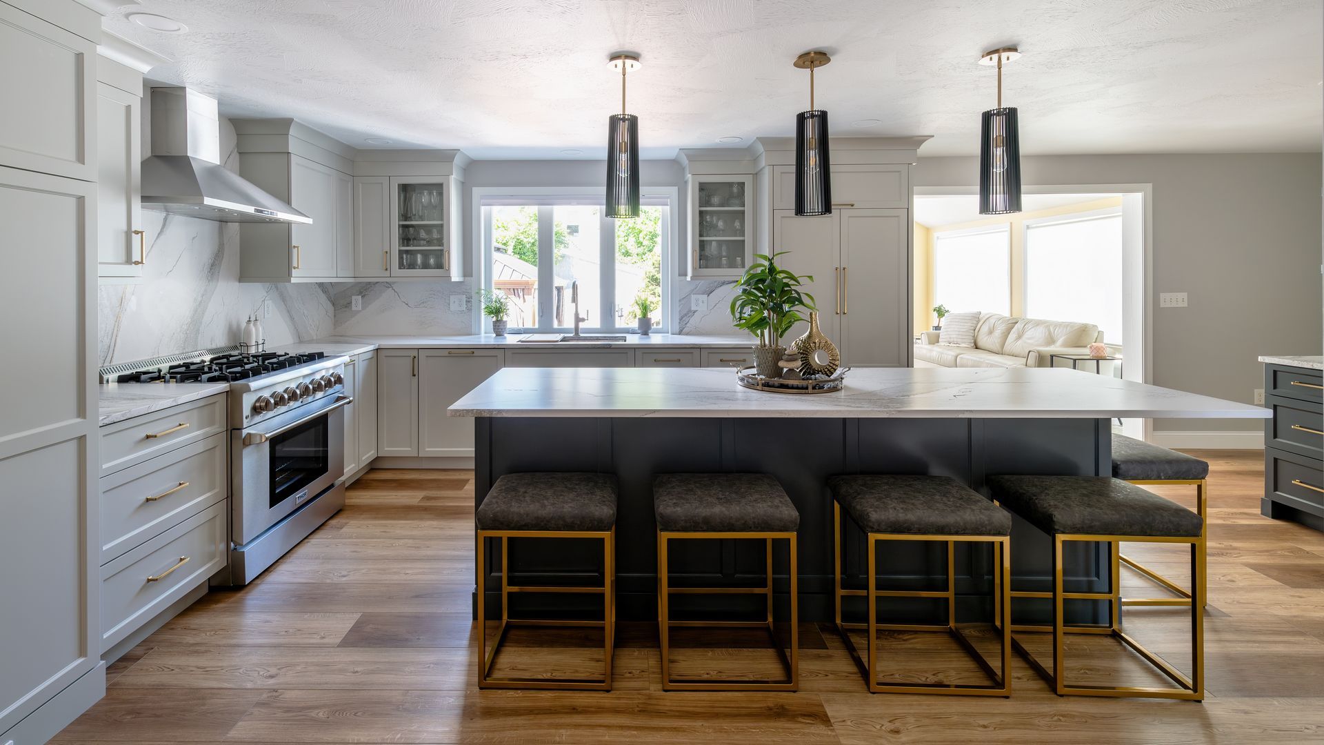 Bright modern kitchen with white cabinets, large island, pendant lights, and four stools