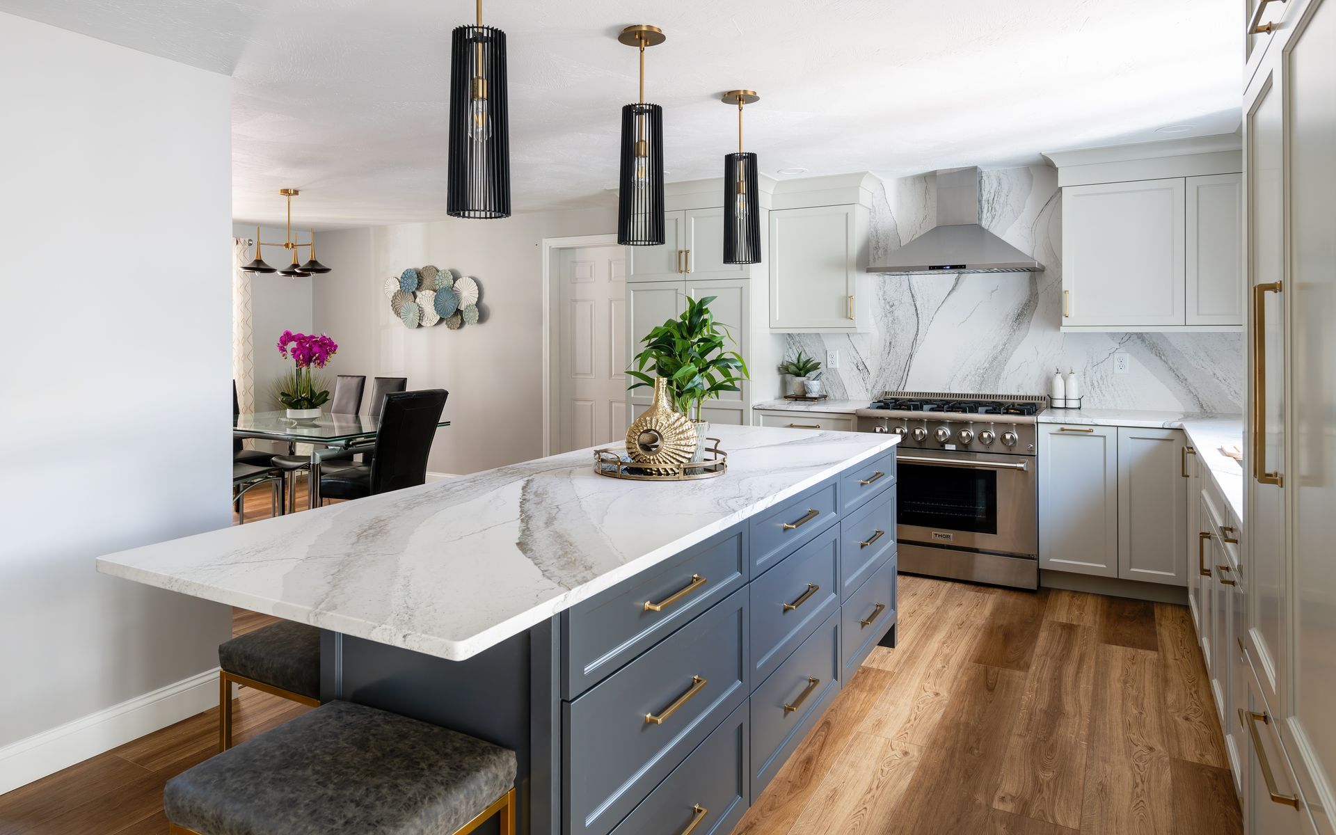 Modern kitchen with blue island, marble countertop, white cabinets, and stainless steel appliances