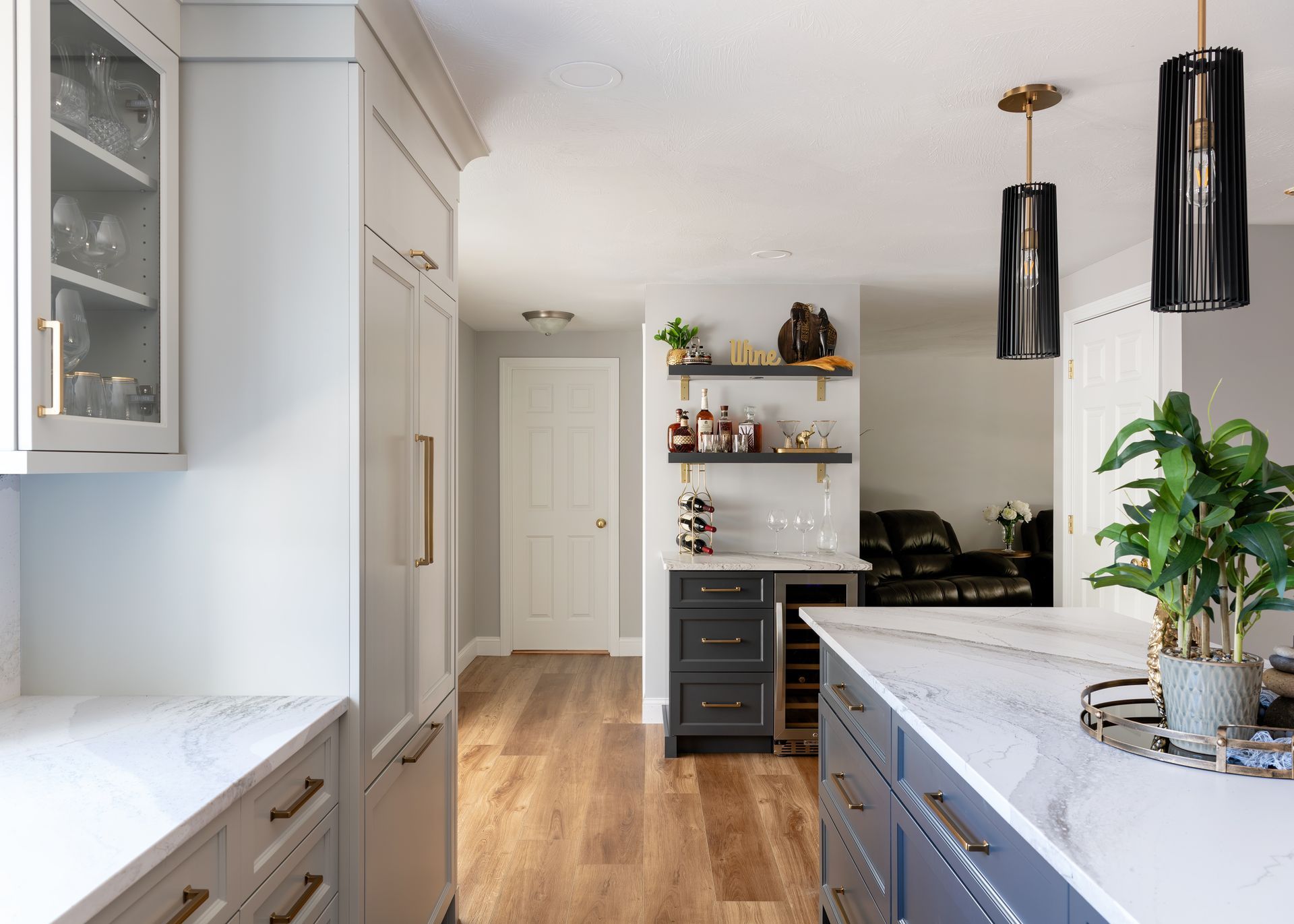 Bright modern kitchen with white cabinets, wood floors, black pendant lights, and a potted plant on the counter